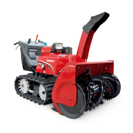 Fraise à neige hybride Honda HSM 1390i IETDR déblayant de la neige sur une allée enneigée avec tarière et chenilles électriques