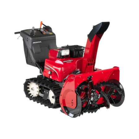Fraise à neige hybride Honda HSM 1380i IETD déblayant de la neige avec tarière et chenilles électriques sur une allée enneigée
